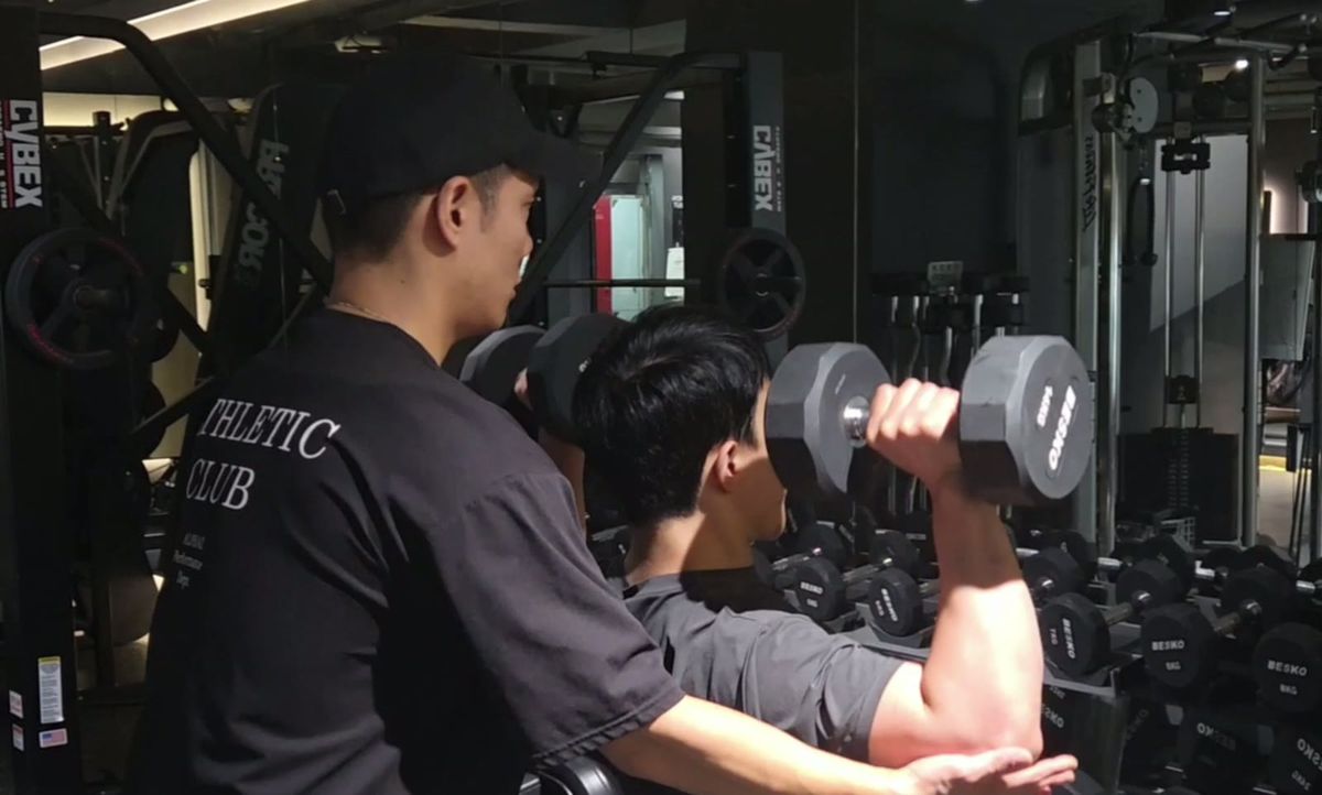덤벨을 든 회원의 팔꿈치를 받쳐 주며 자세를 설명하는 김상현 트레이너