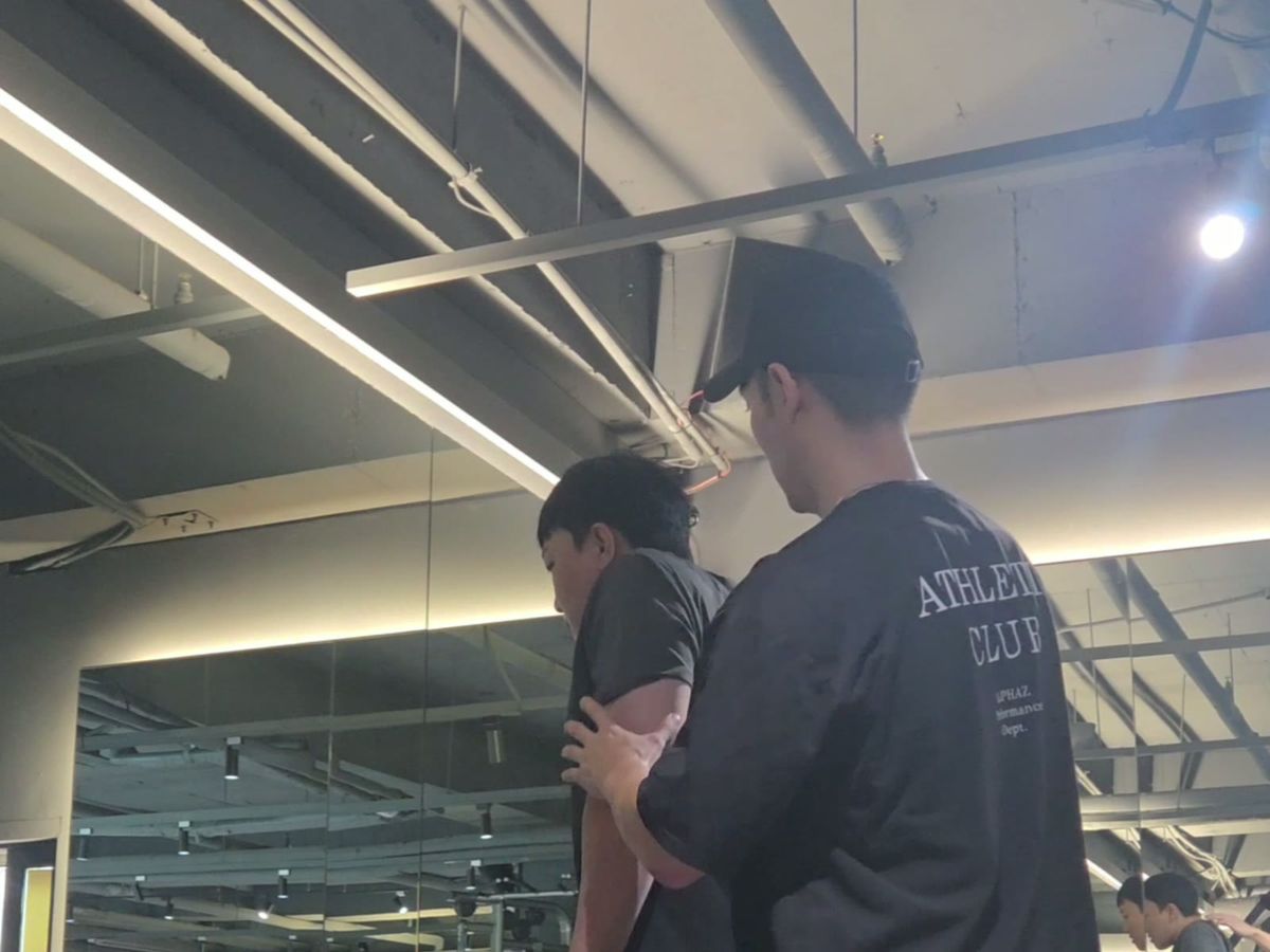 회원 뒤에서 위팔을 받쳐 자세를 고쳐 주는 김상현 트레이너