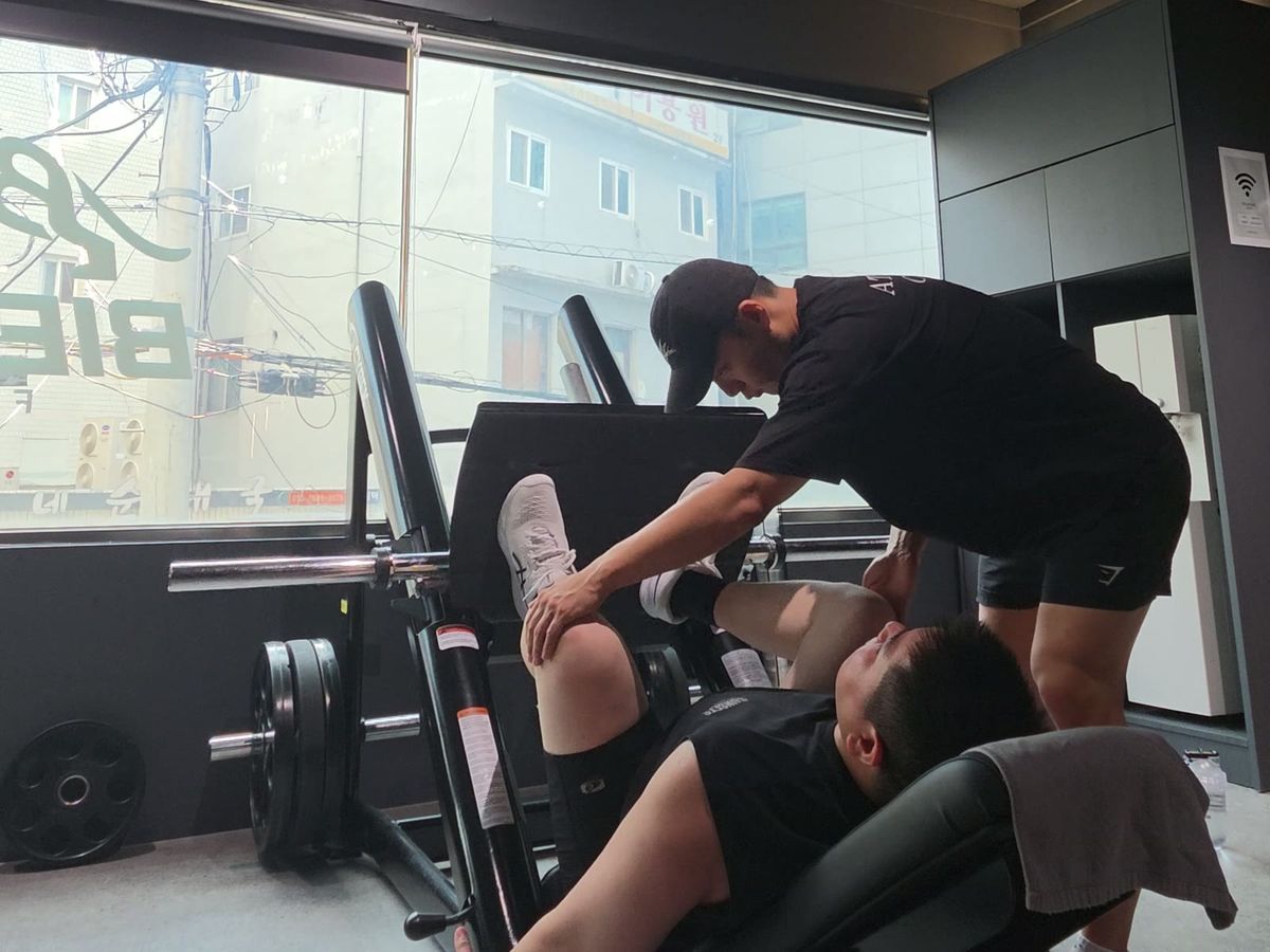 레그 프레스 중인 회원의 다리 위치를 잡아 주는 김상현 트레이너