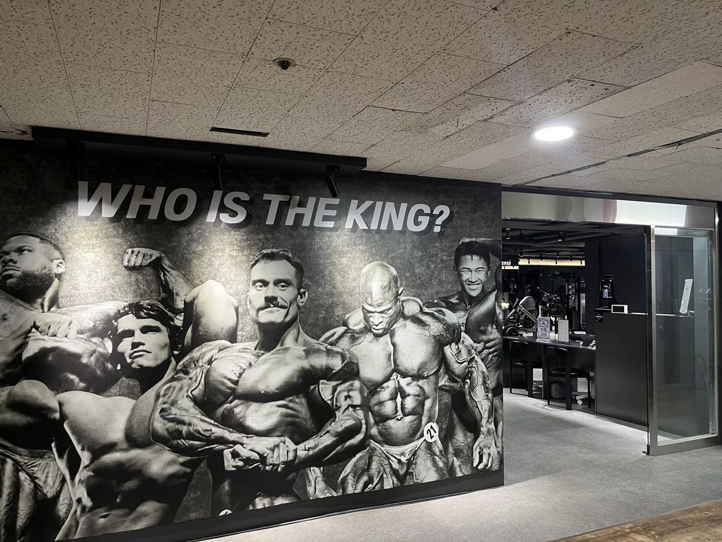 인덕원 메트로빌 2층 복도의 비앤핏 입구. WHO IS THE KING 흑백 벽화 오른쪽에 유리문이 있다